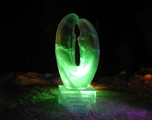 Abstract ice sculpture of two figures, called “Love.” Lit with colored light at night.