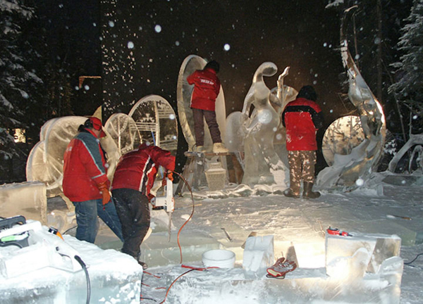 Artists working on ice sculpture “Spring,” at night while it is snowing.