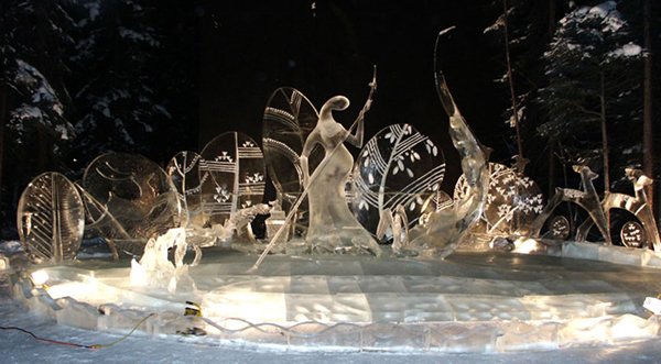 Ice sculpture “Spring,” finished piece lit with white lights, at night.