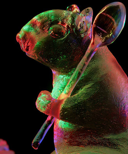 "Time for Tea" ice sculpture of centaur, detail squirrel with spoon. Lit with colored lights against black background at night, red and green colors. Photo by Patrick J. Endres. By Heather Brown, Aaron Costic, Steve Brice and Joan Brice. World Ice Art Championships 2006.