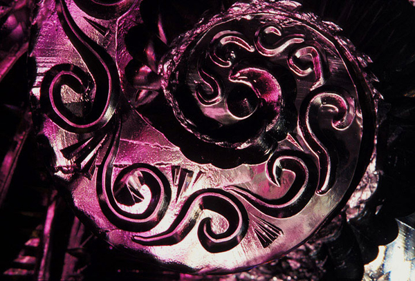 Two abstract figures, a woman and man, Cossack Dancers. Detail of ice ice carving pattern, swirls, under colored lights, deep grapey purple colors. Carving by Vladimir Zhikhartsev and Nadya Fedotova of Russia. Photo by Photo by Patrick J. Endres/AlaskaPhotoGraphics.com.